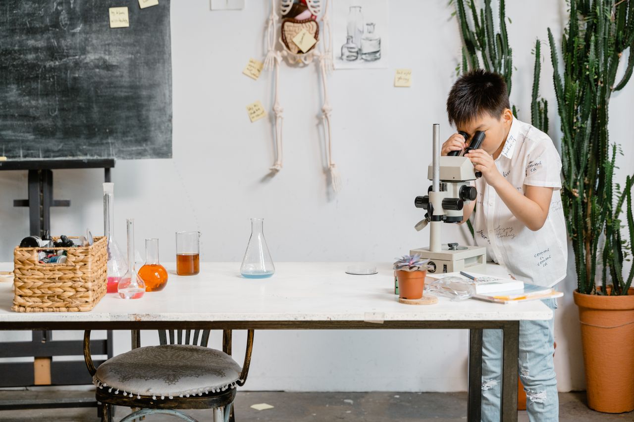 about-01 A young boy in a laboratory examining samples through a microscope for educational purposes.